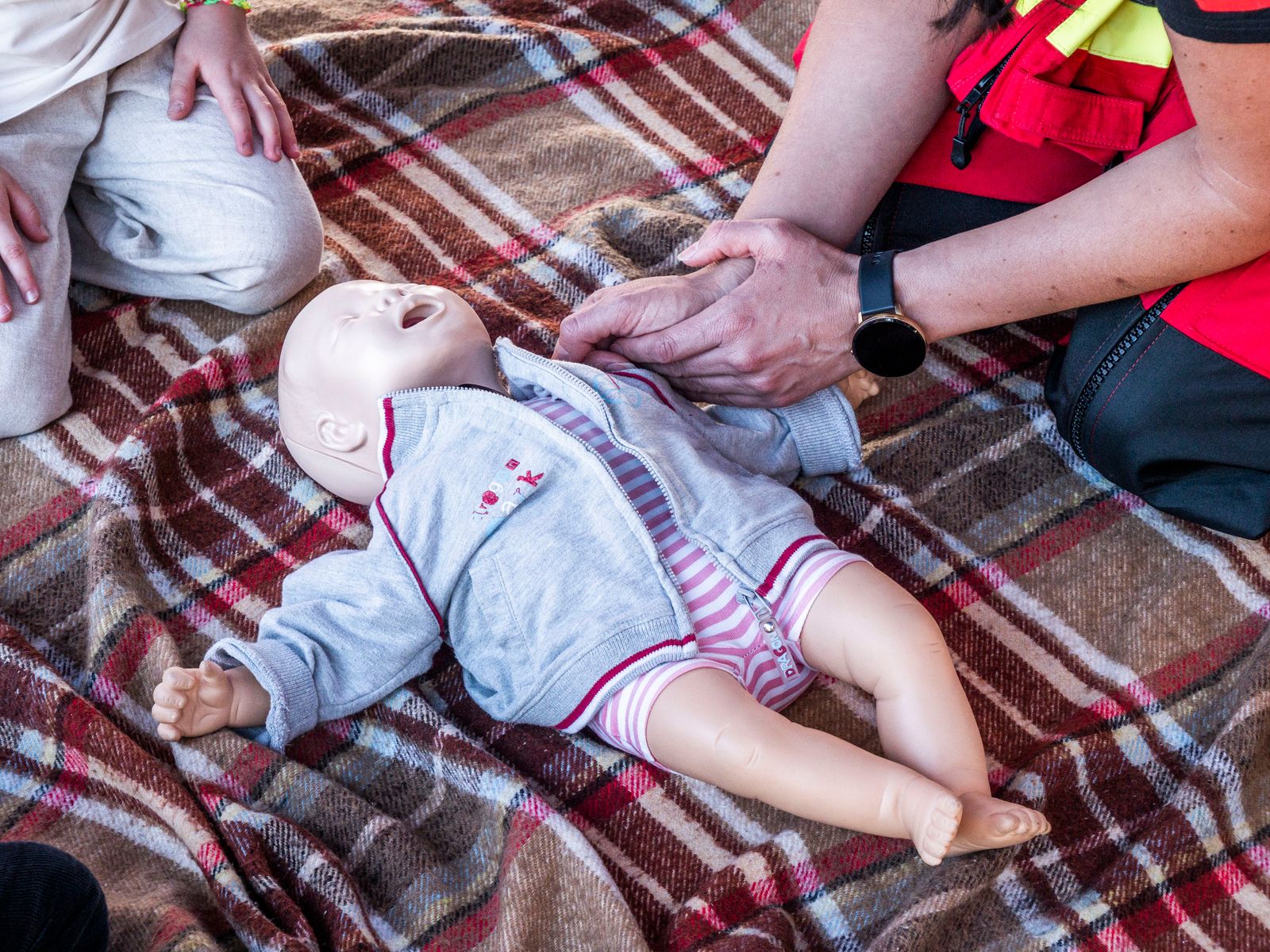 Hands practicing chest compressions on an infant CPR training manikin