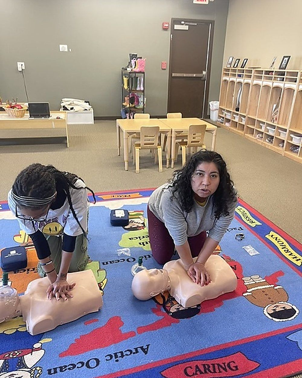 Preschool staff practicing chest compressions on manikins