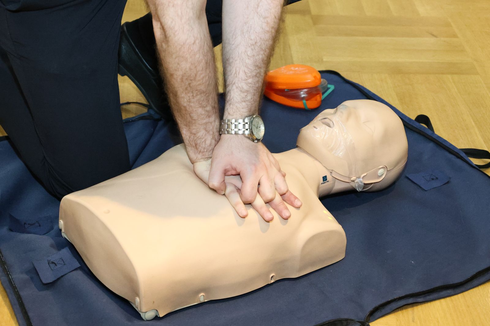 Hands performing chest compressions on a CPR training manikin