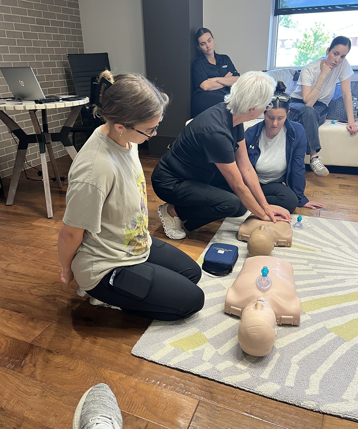 Pam Goldsberry, RN, demonstrating chest compressions on an adult manikin while the class watches
