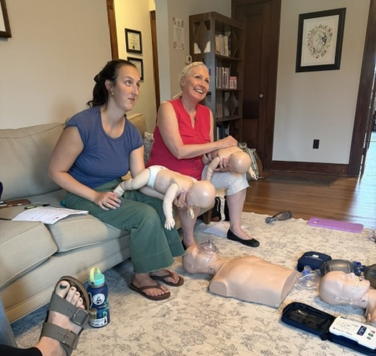 Manikins, bag valve masks and an AED trainer laid out on a training mat