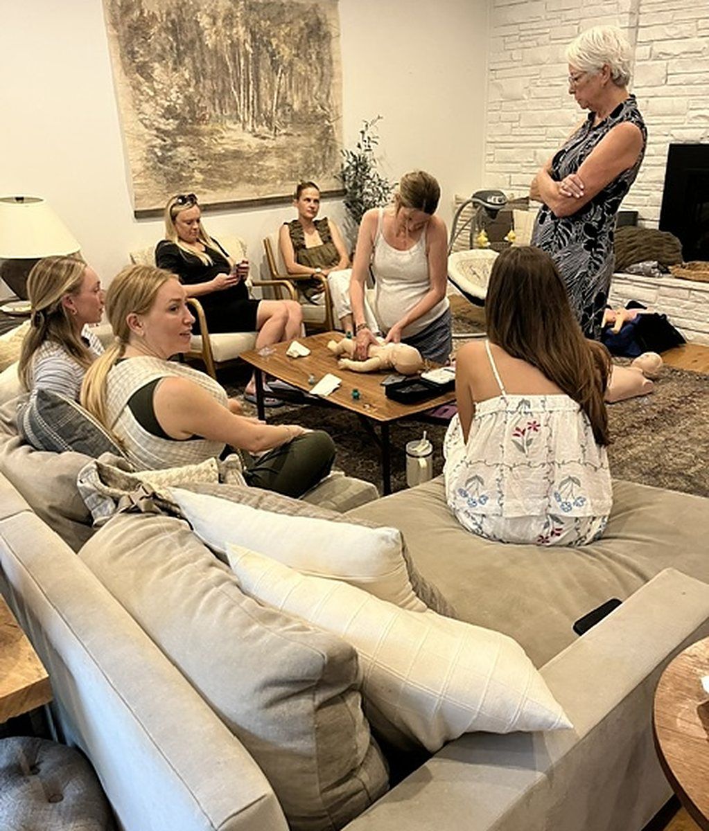 A living room of guests watching an infant CPR demonstration