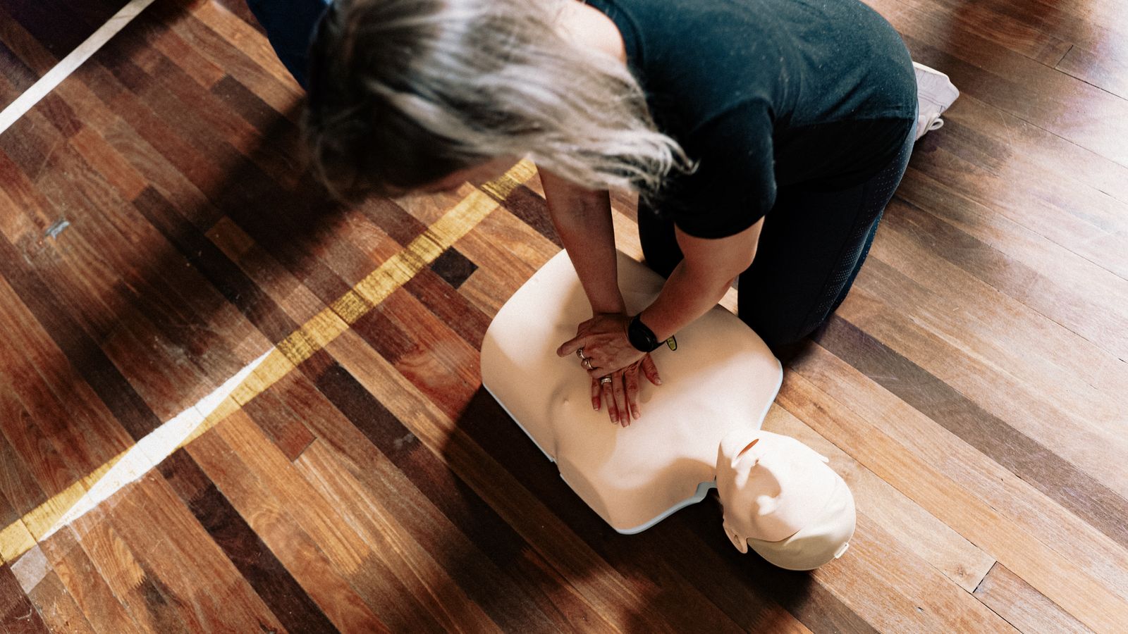 A person practising CPR on a training manikin indoors